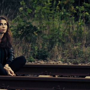 Das Foto einer attraktiven jungen Frau, die auf den Bahngleisen sitzt