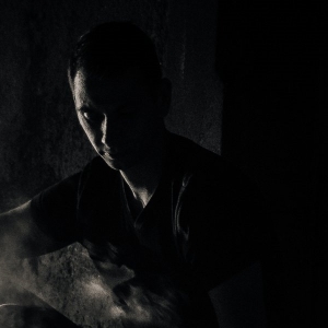 Low-Key Fotografie eines jungen Mannes im Rauch und Gegenlicht